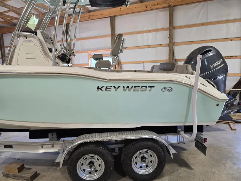 Slide: The Image of 2023 Key West 219 FS boat on trailer in a garage with Yamaha engine. - 16