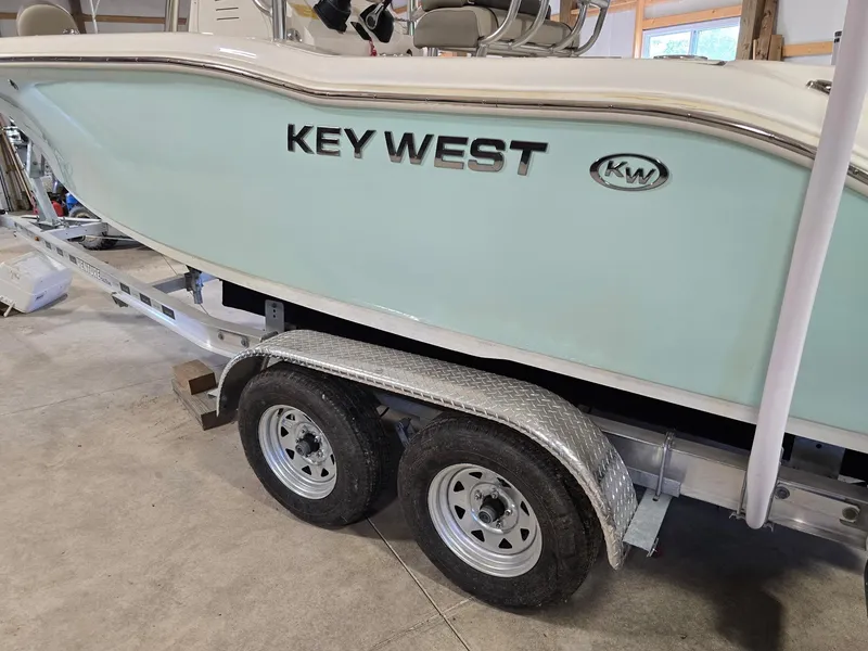 Slide: The Image of 2023 Key West 219 FS boat on trailer in garage setting. - 21