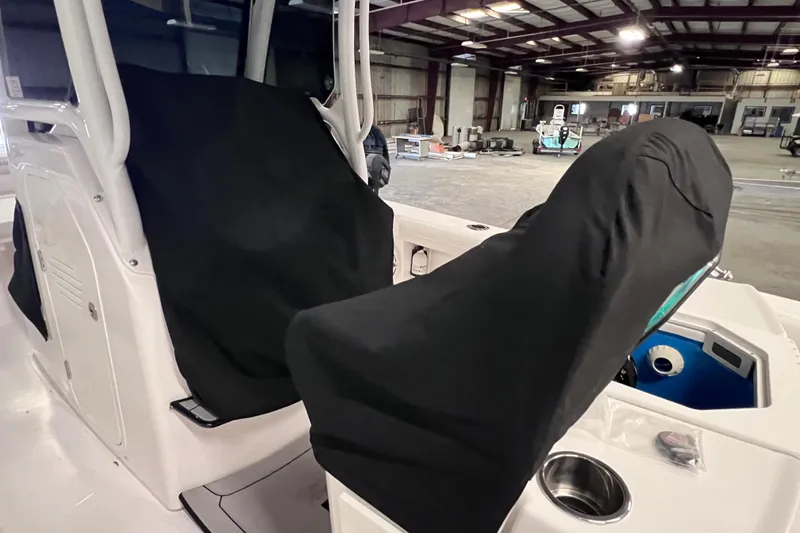 Slide: The Image of 2021 Everglades 253 Center Console boat interior with covered seats in a warehouse. - 5