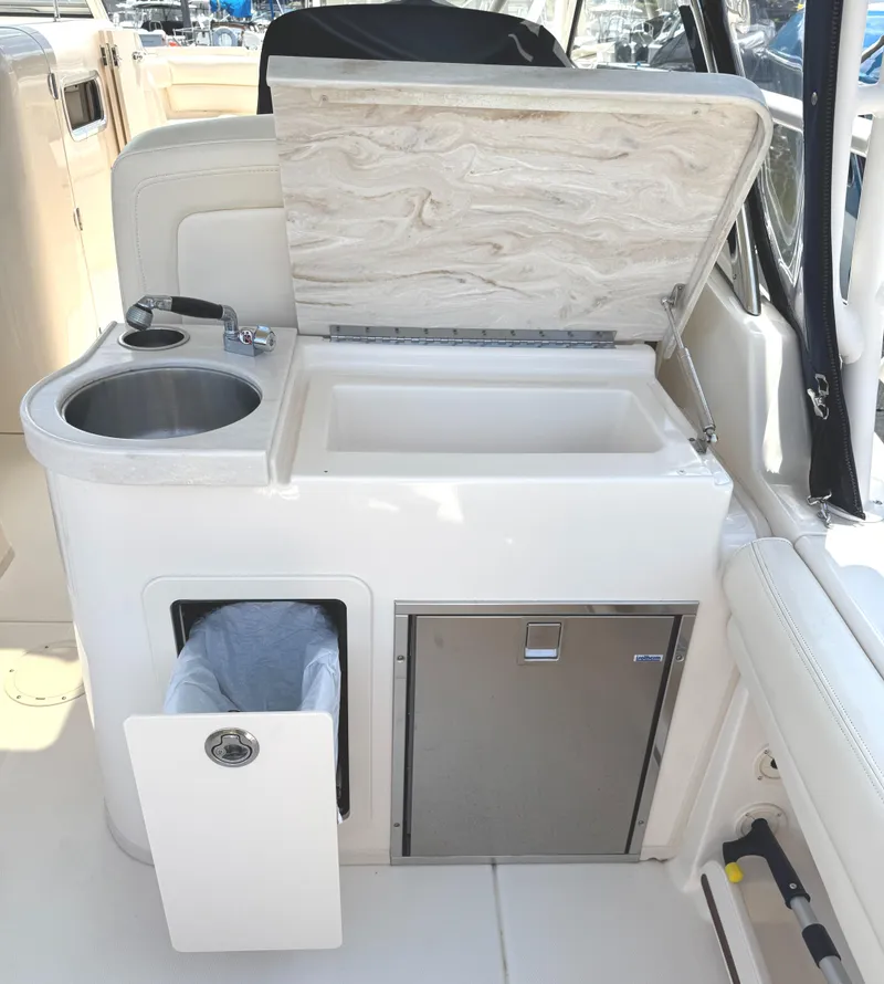 Slide: The Image of 2018 Grady-White Freedom 307 boat interior with sink, storage, and trash compartment. - 23