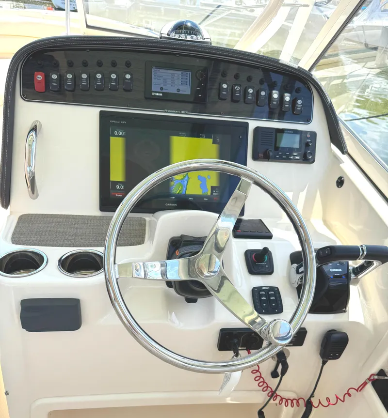 Slide: The Image of 2018 Grady-White Freedom 307 boat dashboard with steering wheel and navigation controls. - 9