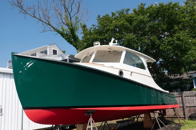 The Image of 1997 Belkov Picnic Express boat with green hull and red bottom, displayed outdoors. - 0