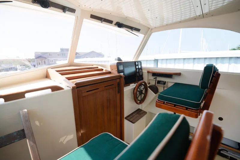 Slide: The Image of Interior of 1997 Belkov Picnic Express boat with green cushioned seating and wooden accents. - 10