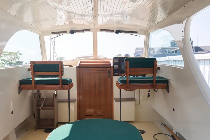 Slide: The Image of Interior of a 1997 Belkov Picnic Express boat with green cushioned seating. - 13