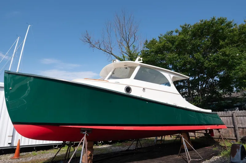 Slide: The Image of 1997 Belkov Picnic Express boat on stands, green hull, red bottom, clear sky background. - 21