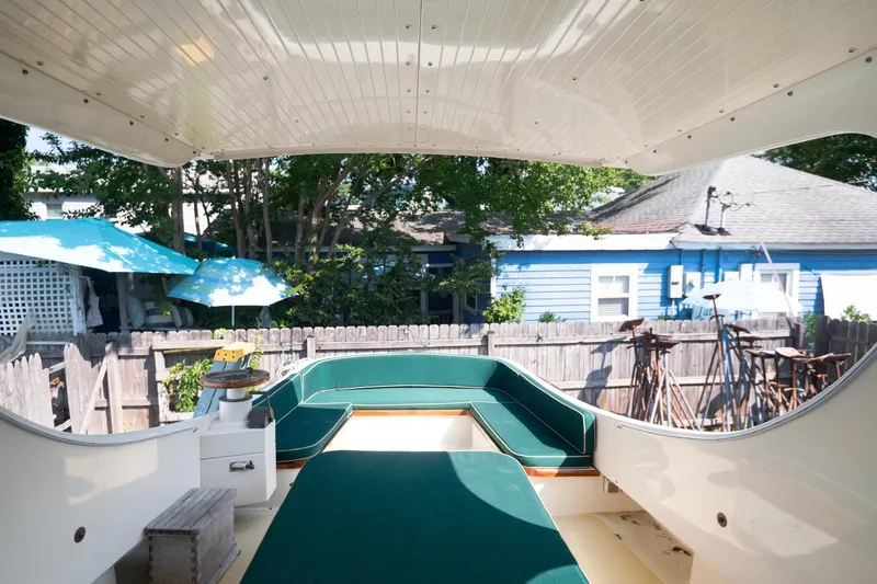 Slide: The Image of 1997 Belkov Picnic Express boat interior with green seating, outdoor setting, and blue umbrellas. - 8