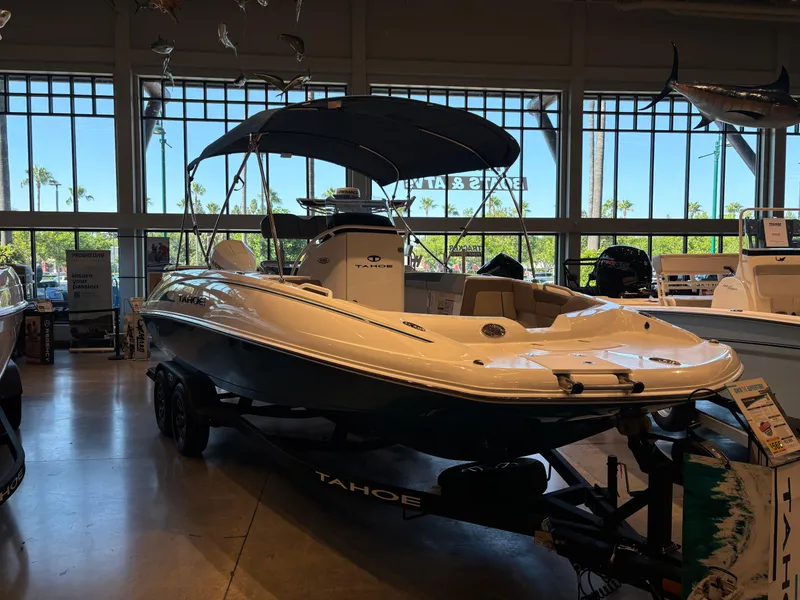 Slide: The Image of 2025 Tahoe 2150 CC boat displayed indoors with canopy and trailer. - 1