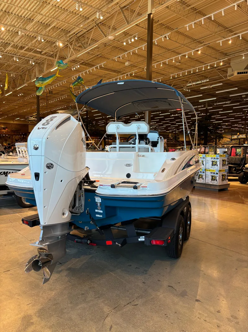 Slide: The Image of 2025 Tahoe 2150 CC boat displayed indoors with outboard motor and canopy. - 2