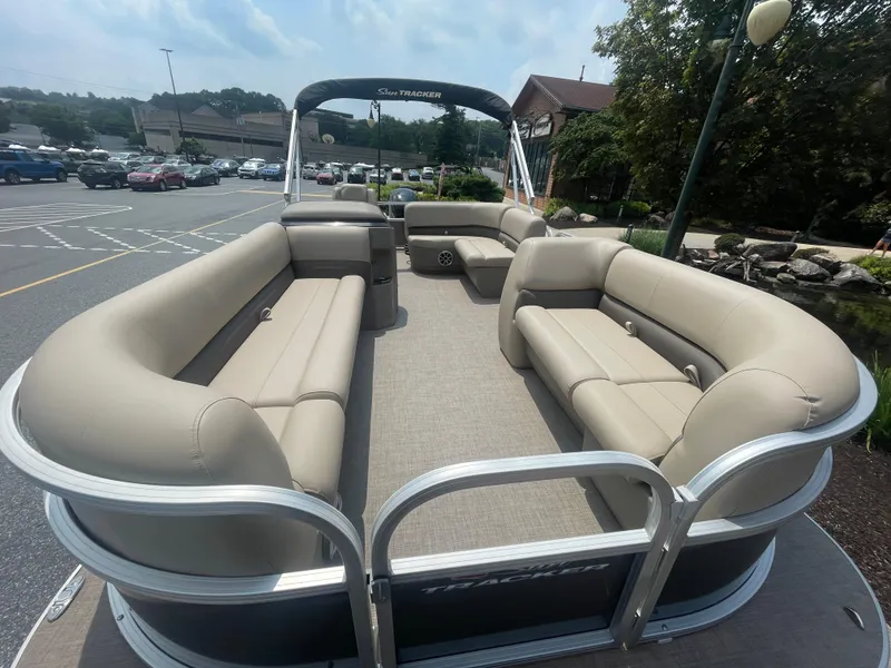 Slide: The Image of 2025 Sun Tracker Party Barge 18 DLX pontoon boat with spacious seating in a parking lot. - 2