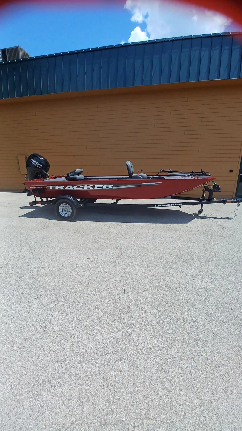The Image of 2025 Tracker Panfish 17 boat on trailer, parked outdoors against a yellow wall. - 0