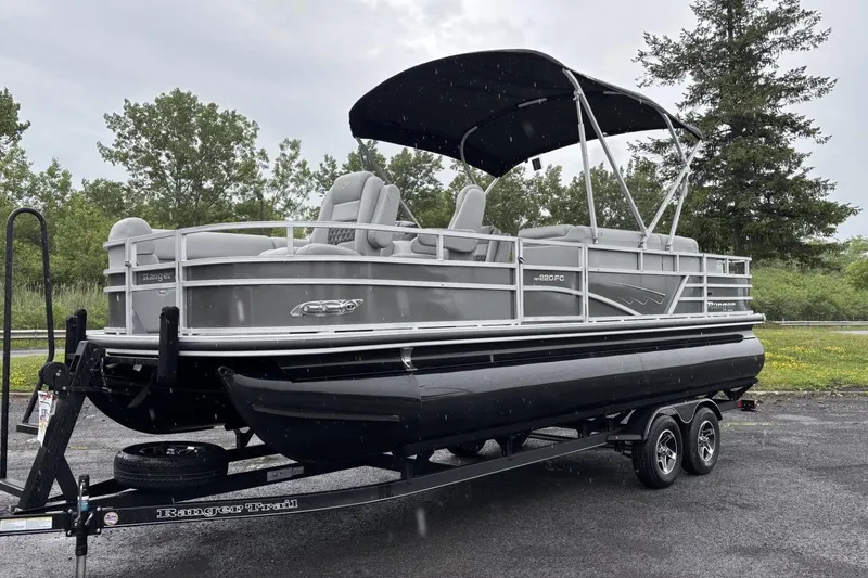 The Image of The image shows a gray pontoon boat on a trailer. It features a black canopy. - 0