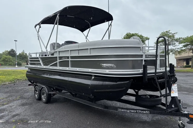 Slide: The Image of 2025 Ranger Reata 220FC pontoon boat with black trailer, gray canopy, and spacious deck. - 1