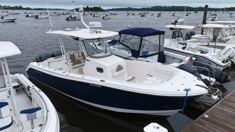 Slide: The Image of 2015 Edgewater 280CC boat docked among other vessels on a calm lake. - 2