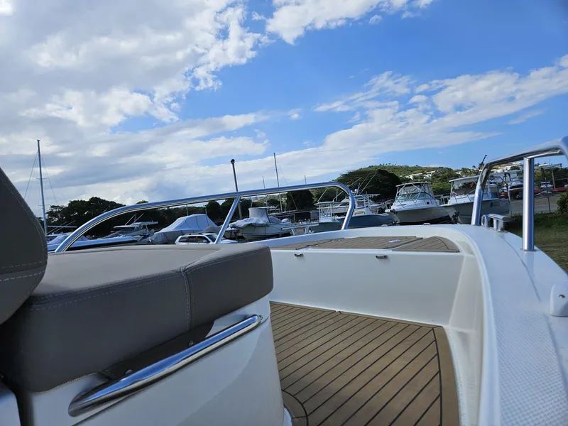 Slide: The Image of 2023 Nimbus Tender 8 boat with sleek design, docked under a partly cloudy sky. - 13