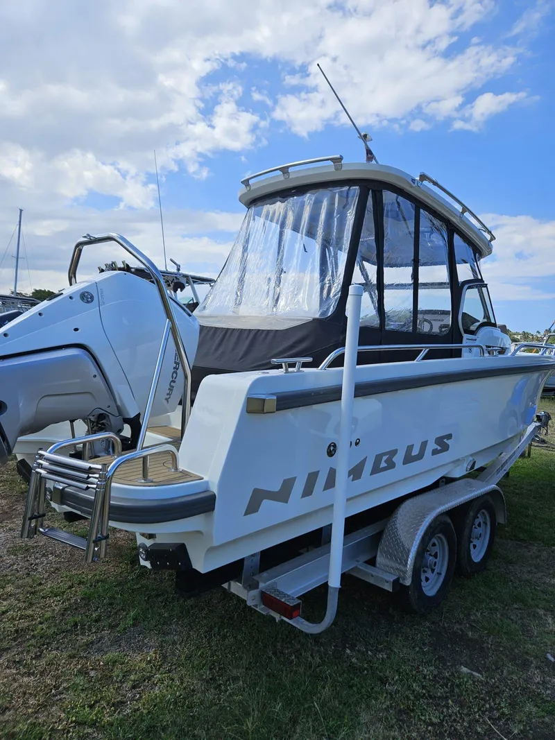 Slide: The Image of 2023 Nimbus Tender 8 boat on trailer, parked outdoors under a partly cloudy sky. - 2