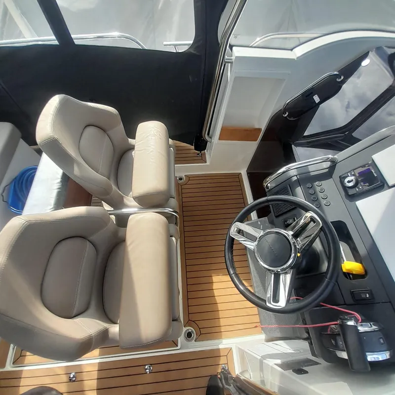 Slide: The Image of Interior of 2023 Nimbus Tender 8 boat with steering wheel and beige seats. - 4