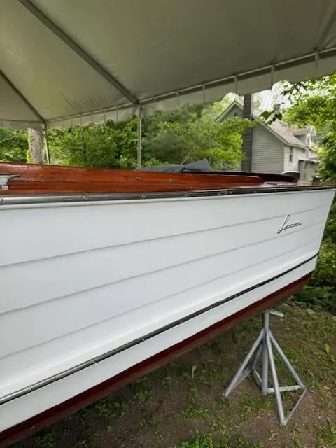 Slide: The Image of 1968 Lyman 19 boat under a canopy, showcasing its classic white and wood design. - 3