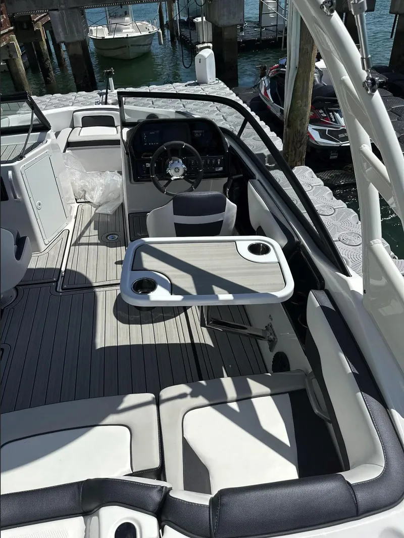 Slide: The Image of 2023 Yamaha Boats AR195S interior with steering wheel, seating, and table on a sunny day. - 6