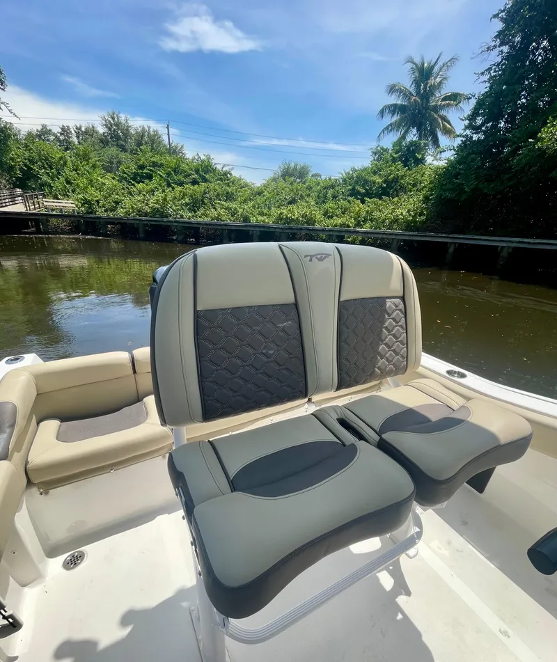 Slide: The Image of 2022 Tidewater 210 LXF boat interior with stylish seating, surrounded by lush greenery. - 2