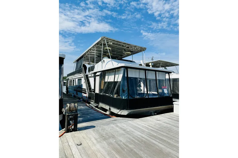 The Image of 1992 Sumerset 66 houseboat on a serene lake with lush forest backdrop. - 0