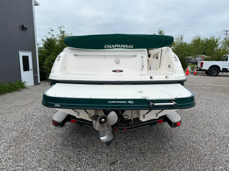 Slide: The Image of 1999 Chaparral Sunesta 232 boat, rear view, parked on gravel near a building. - 2