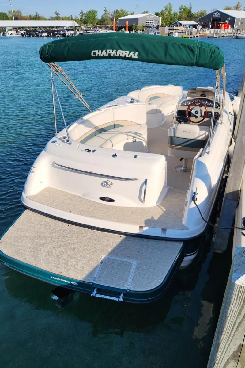 Slide: The Image of 1999 Chaparral Sunesta 232 boat docked, featuring green canopy and spacious seating. - 7