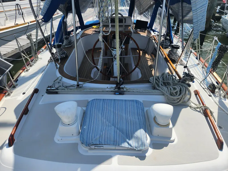 Slide: The Image of 1989 Taswell 43 sailboat deck with ropes, wheel, and striped cushion in marina. - 11