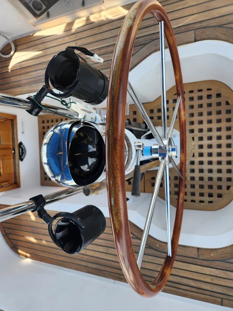 Slide: The Image of Steering wheel and compass of a 1989 Taswell 43 sailboat, featuring wooden and metal elements. - 15