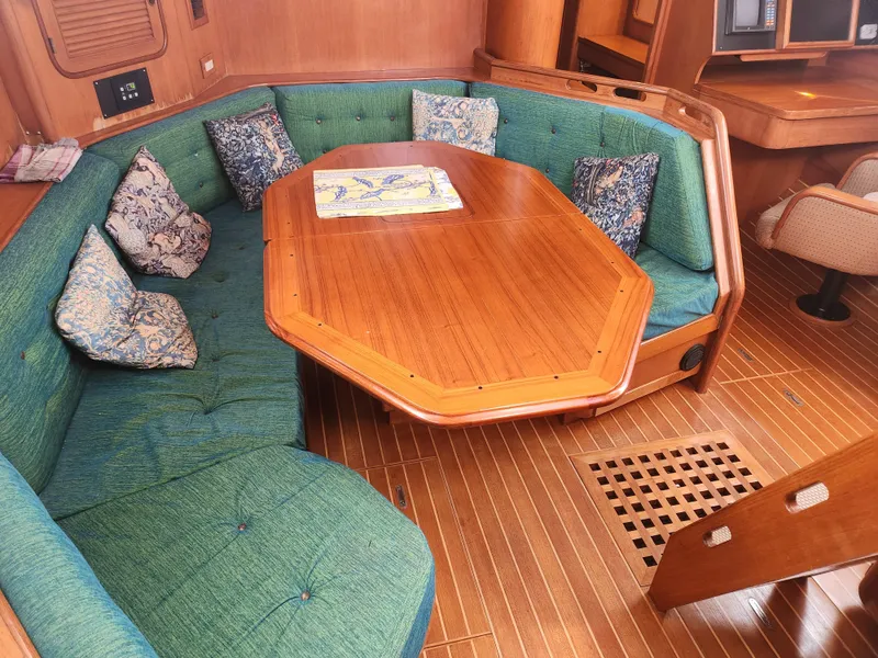 Slide: The Image of Interior of 1989 Taswell 43 yacht with wooden table, green seating, and patterned cushions. - 29