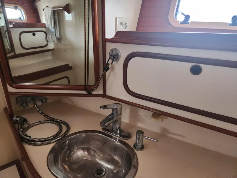 Slide: The Image of Bathroom sink area in a 1989 Taswell 43 yacht, featuring a mirror and porthole. - 44