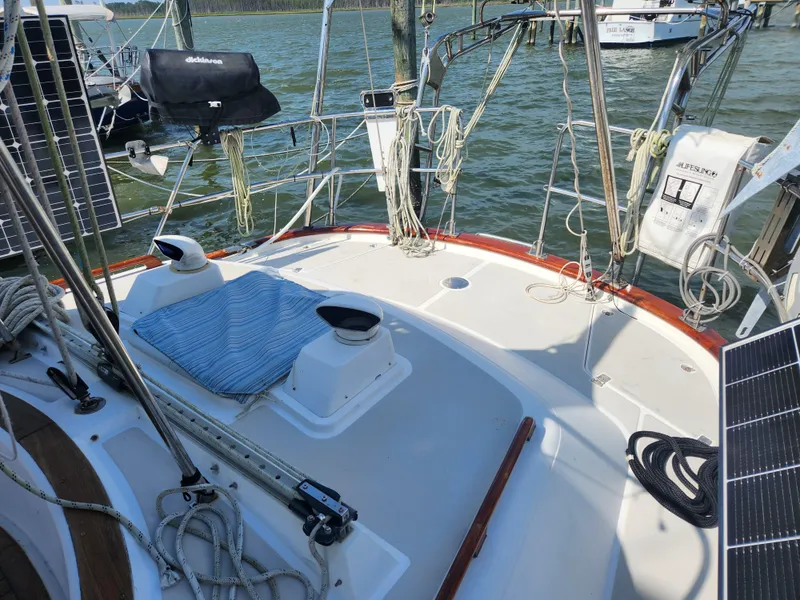 Slide: The Image of 1989 Taswell 43 sailboat deck with ropes, solar panels, and lifebuoy on calm water. - 9