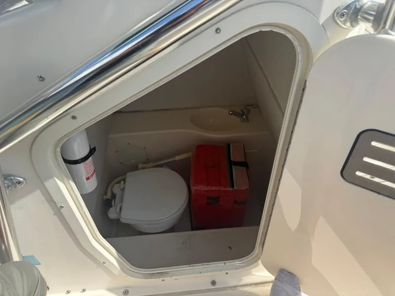 Slide: The Image of 2002 Pursuit 2470 CC boat interior with toilet and storage compartment. - 11