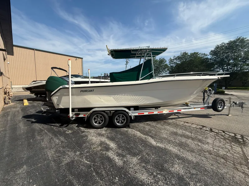 Slide: The Image of 2002 Pursuit 2470 CC boat on trailer, parked outdoors under a clear sky. - 20