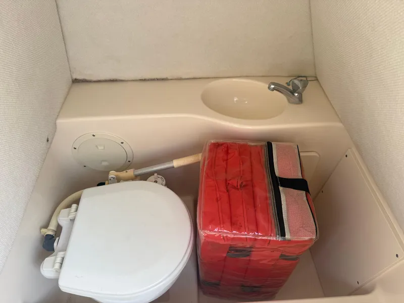 Slide: The Image of Compact boat bathroom with toilet, sink, and red life jacket storage on a 2002 Pursuit 2470 CC. - 6