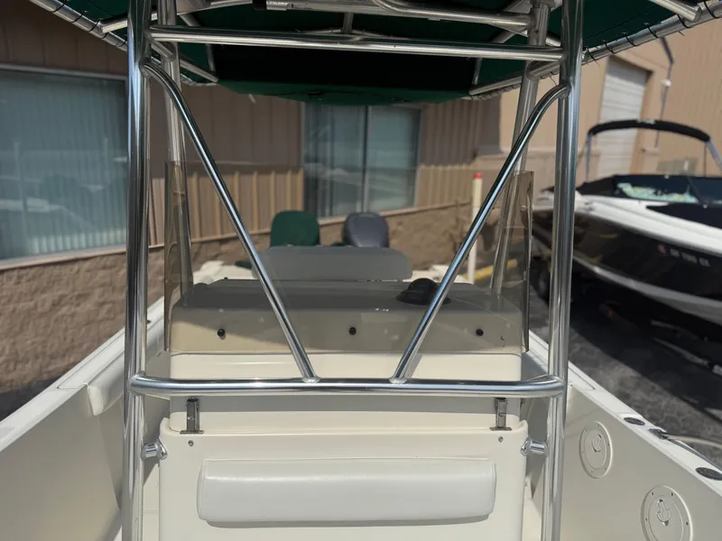 Slide: The Image of 2002 Pursuit 2470 CC boat interior with T-top and console, parked outdoors. - 7