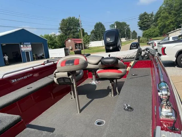 Slide: The Image of Red 2011 Ranger 618 T boat with seating, parked outdoors near buildings and vehicles. - 9