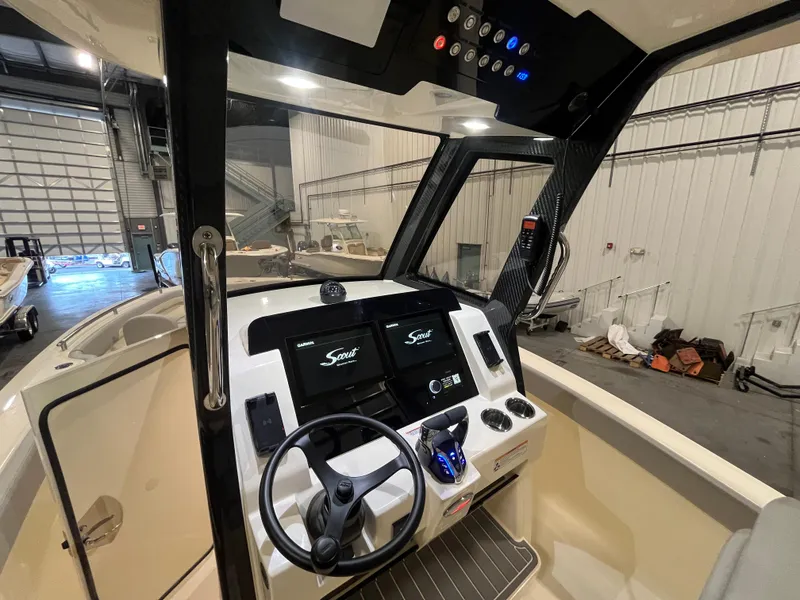 Slide: The Image of 2026 Scout 260 LXF boat dashboard with modern controls and dual displays in a showroom. - 15