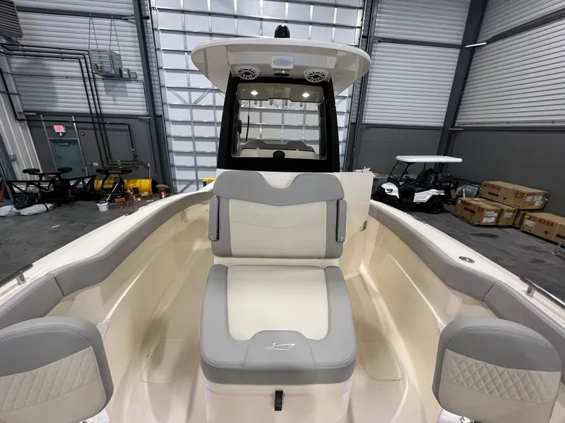 Slide: The Image of 2026 Scout 260 LXF boat interior with gray and white seating in a warehouse setting. - 18