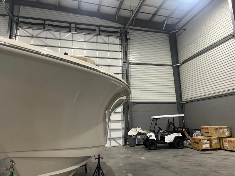 Slide: The Image of 2026 Scout 260 LXF boat in storage with golf cart and Yamaha boxes nearby. - 5