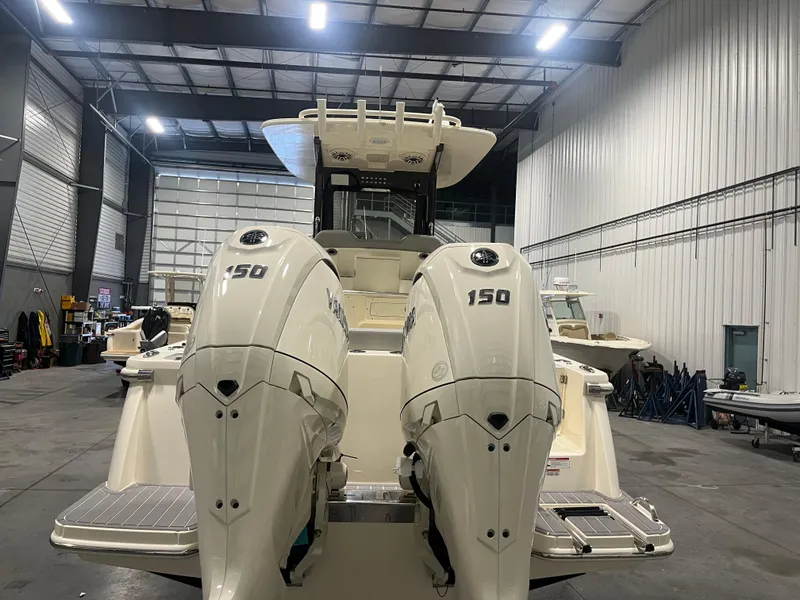 Slide: The Image of 2026 Scout 260 LXF boat with dual 150 horsepower engines in a spacious indoor facility. - 7