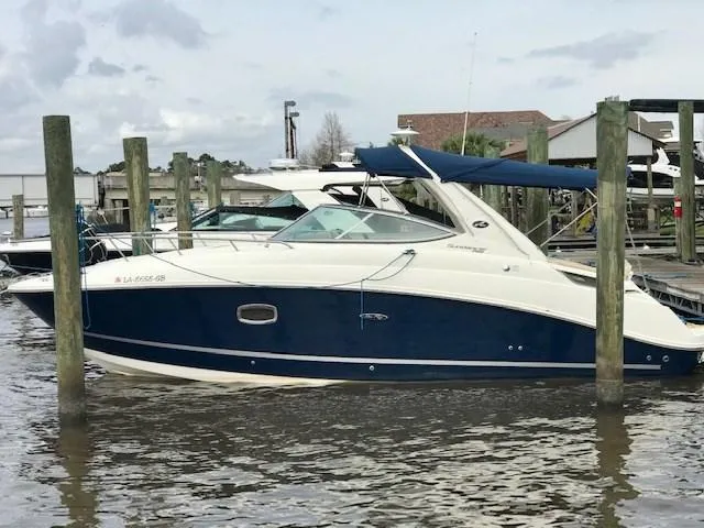 Slide: The Image of 2012 Sea Ray 280 Sundancer boat docked at marina, featuring blue and white exterior. - 0
