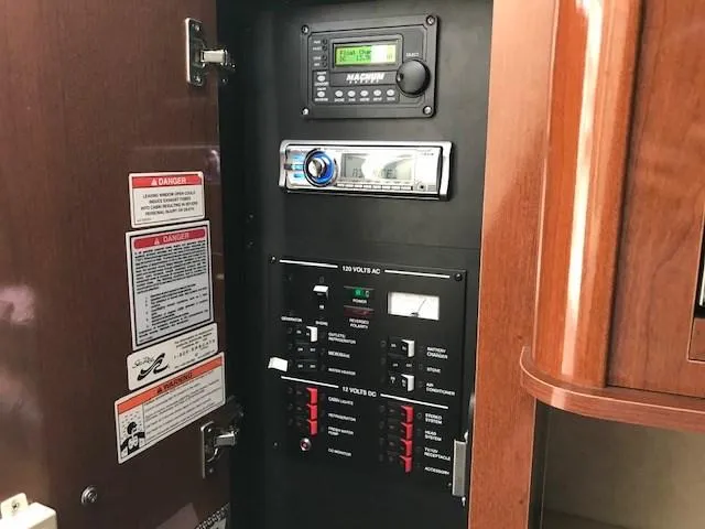 Slide: The Image of Electrical control panel inside 2012 Sea Ray 280 Sundancer boat, featuring stereo and warning labels. - 18