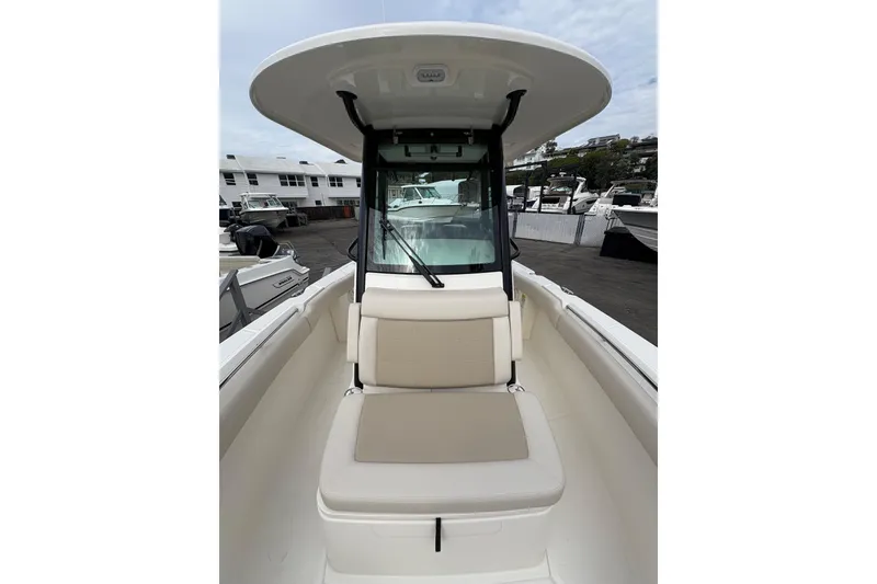 Slide: The Image of 2026 Boston Whaler 250 Outrage boat interior with seating and console, docked at marina. - 9