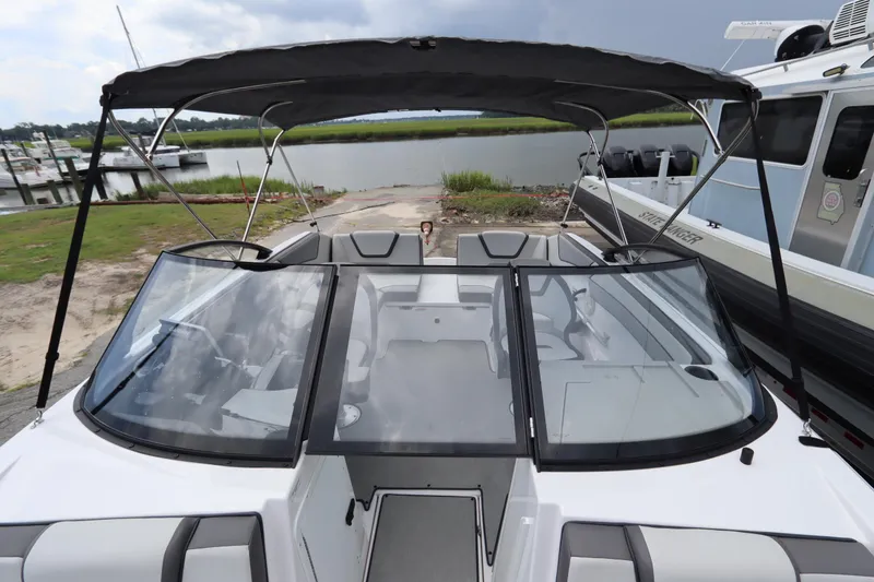 Slide: The Image of 2024 Yamaha Boats SX220 with canopy, docked near a serene waterfront. - 14