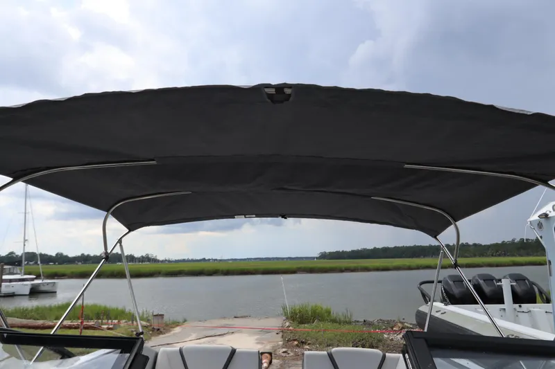 Slide: The Image of 2024 Yamaha Boats SX220 with canopy, docked by a serene river under cloudy skies. - 27