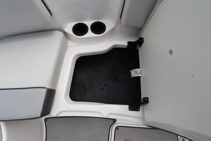 Slide: The Image of 2024 Yamaha Boats SX220 storage compartment with cup holders and open hatch. - 31