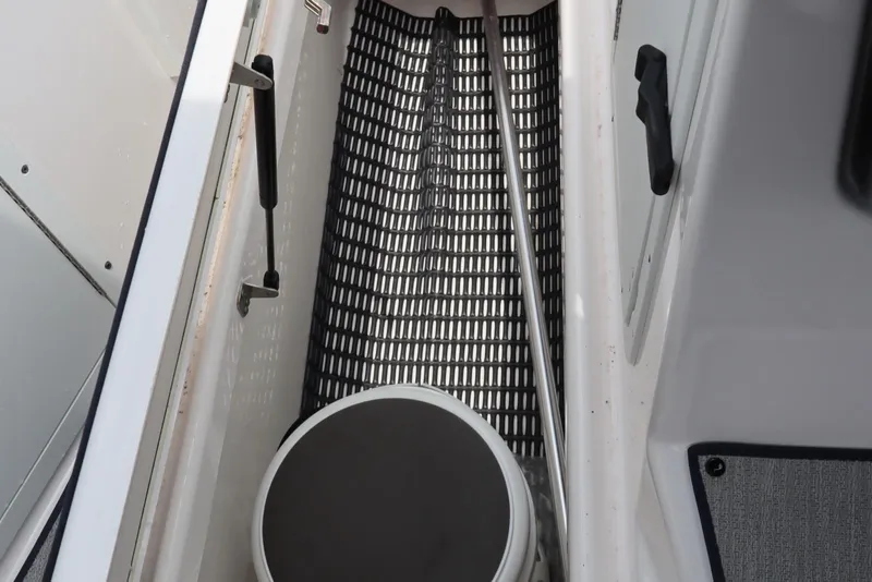 Slide: The Image of 2024 Yamaha Boats SX220 interior storage compartment with black grid flooring. - 34