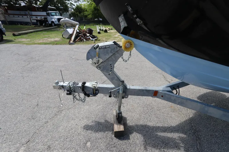 Slide: The Image of Trailer hitch of 2024 Yamaha Boats SX220 on pavement, with background equipment. - 35