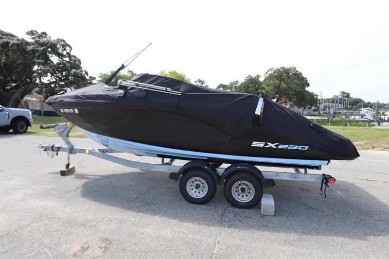 Slide: The Image of 2024 Yamaha Boats SX220 covered on trailer, parked outdoors. - 38
