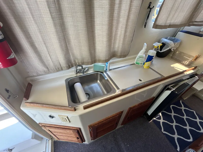 Slide: The Image of 2005 Rosborough RF-246 Custom Wheelhouse kitchen with sink, cleaning supplies, and wooden cabinets. - 9